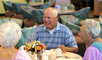 man sitting at table with others laughing