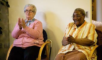 2 people sitting in chairs clapping their hands