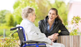 woman in wheelchair talking to other woman who is smiling and listening
