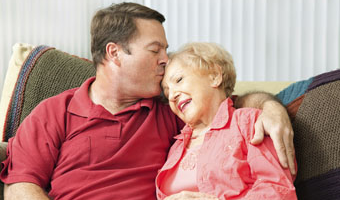 man kissing older woman's forehead