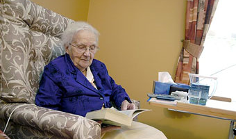 older woman sitting in armchair reading